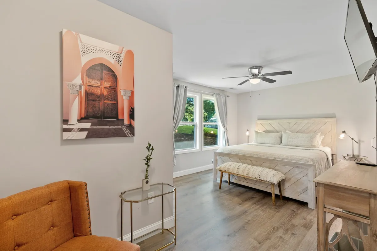 King bedroom with a tufted headboard, bench and bright windows